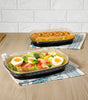CE Disposables aluminum foil tray with clear lid holding fresh salad and another with baked pasta on wooden table